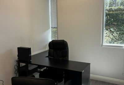 Bright corner office with black furniture and natural light from a large window.