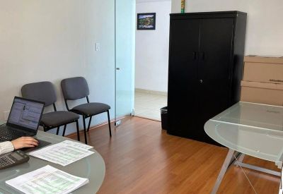 Bright workspace with a round glass table, wooden floors, and a black storage cabinet.