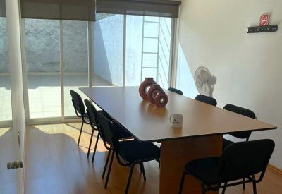 Professional meeting room with a large wooden table, black chairs, and sliding glass doors.