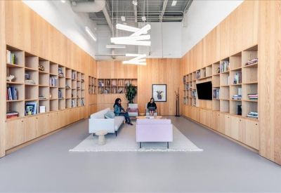 Open-plan workspace with multiple desks and modern zigzag overhead lighting.