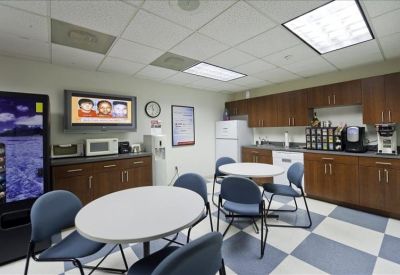 Breakroom with dining tables, kitchen cabinets, and a blue-and-white checkered floor.