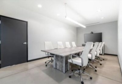 Sleek conference room with a large wooden table and white executive chairs.
