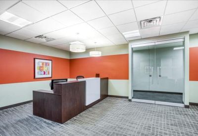 Branded reception area with a dark wood front desk and vibrant orange accent walls.