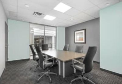 Professional meeting room featuring a light wood table, black ergonomic chairs, and a feature wall.