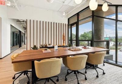 Elegant communal dining area with a long wooden table, yellow armchairs, and a large window.