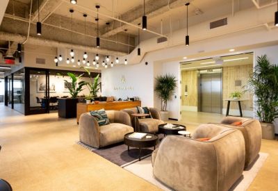 Modern lobby area with velvet armchairs, circular coffee tables, and a branded wood reception desk.