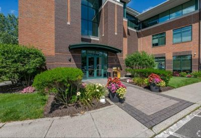 Close-up of the building entrance featuring a green awning and colourful flower pots.