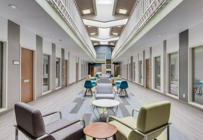 Bright multi-level communal atrium with colorful armchairs and skylights.