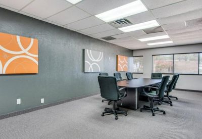 Spacious boardroom featuring gray walls, orange wall art, and a large dark conference table.