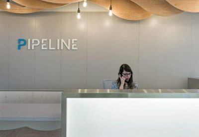 Modern reception desk with a glowing front panel and unique wave-patterned wooden ceiling.