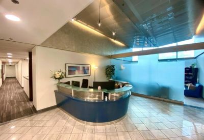 Modern curved blue reception desk under recessed lighting and a reflective ceiling.