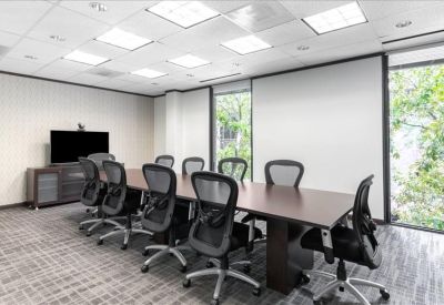 Spacious boardroom with a long wooden table, mesh chairs, and a large display screen.