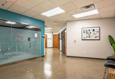 Modern corridor with polished floors, teal accent walls, and glass-partitioned office spaces.