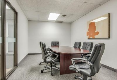 Meeting room with a wooden oval table, black leather chairs, and colorful wall art.