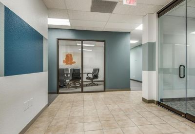 Hallway with tiled flooring and a view into a private glass-walled office.