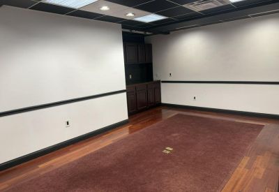 Large meeting room with wood-style flooring and a dark built-in cabinet.
