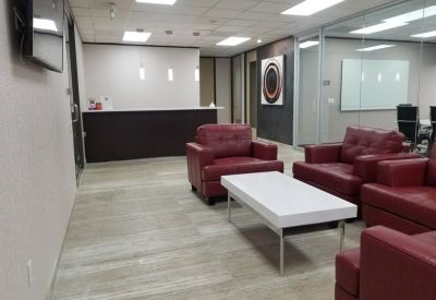 Professional reception area featuring red leather armchairs and a dark front desk.