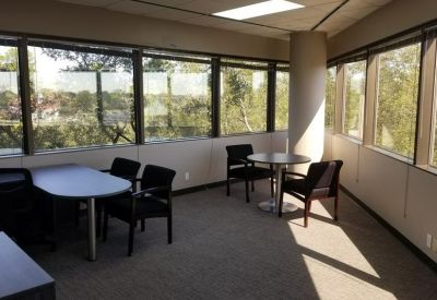Private office space with large windows overlooking trees and a small meeting table.