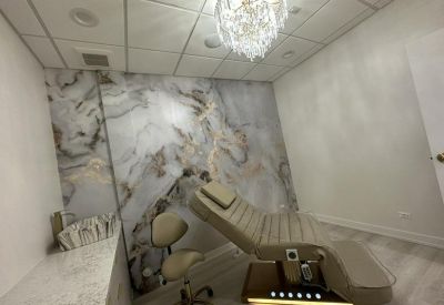 Modern treatment suite featuring a crystal chandelier and marble-textured accent wall.