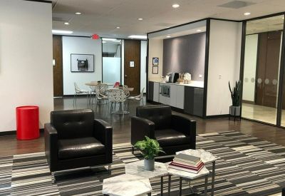 Modern communal lounge with black leather armchairs, striped carpet, and a coffee station.