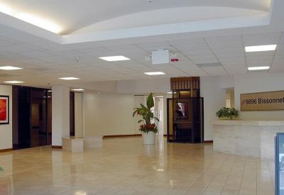 Spacious building lobby with polished floors, a reception desk, and indoor greenery.