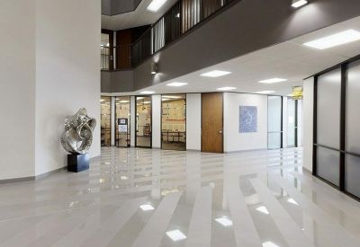 Spacious multi-story lobby with a silver abstract sculpture and high-gloss floors.