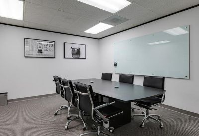 Conference room with a black table, leather chairs, and a large frosted glass whiteboard.
