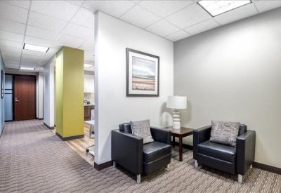 Seating area with two leather armchairs, a side table, and a hallway view.