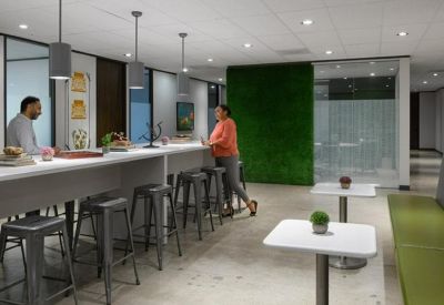 Bright communal break area with a green moss wall and high-top seating.