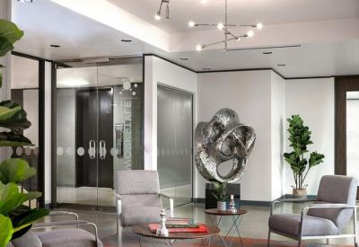 Elegant reception lounge featuring grey armchairs and a large silver sculpture.