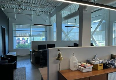 Bright open-plan office with white dividers, wooden storage, and large windows.