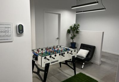 Relaxation area with a foosball table, modern black armchair, and a potted plant.