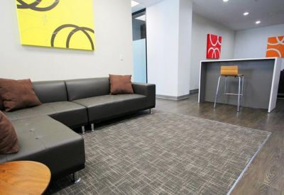 Modern lounge area with a dark leather sectional sofa and vibrant yellow abstract wall art.