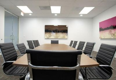 Professional conference room with a large wooden table, black ergonomic chairs, and modern art.