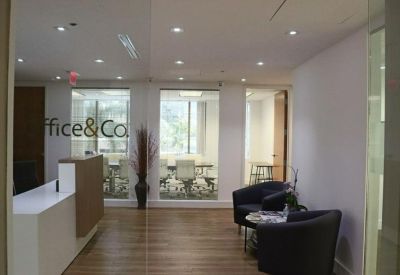 Modern reception area with a sleek white desk and a branded glass partition.