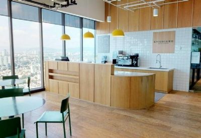 Bright office kitchen area with light wood cabinetry, yellow pendant lights, and a coffee station.