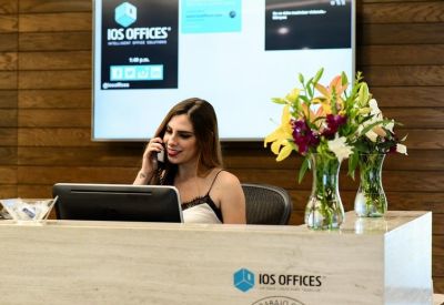 Modern reception desk with a receptionist on the phone and fresh floral arrangements.