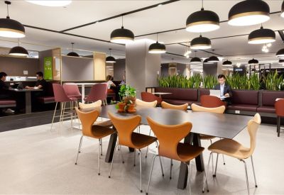 Coworking lounge with warm wood accents and contemporary black pendant lighting.