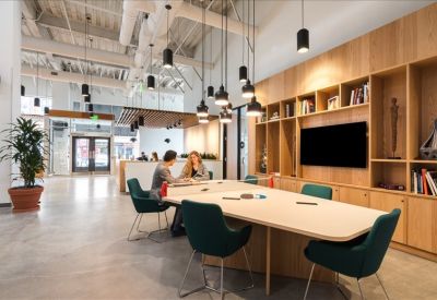 Large shared workspace featuring long wooden tables and stylish teal seating.