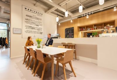 Bright dining area with white tables and a wood-accented coffee bar.