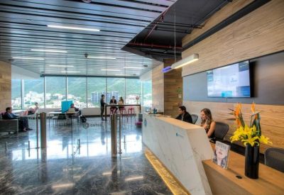 Bright reception area with a marble front desk, wooden walls, and a large TV screen.