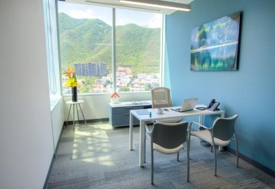 Private office featuring a white desk, blue accent wall, and floor-to-ceiling windows.