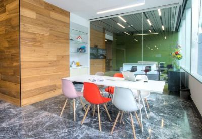 Meeting room with colorful chairs around a white table and a wood-paneled feature wall.