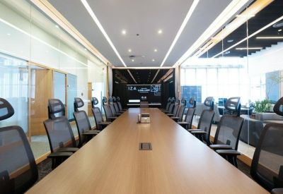 Long wooden boardroom table with ergonomic mesh chairs and a large wall monitor.