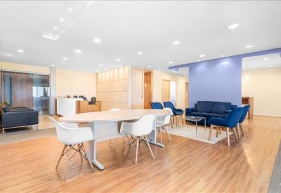 Spacious communal lounge with a large table, blue sofas, and wooden flooring.