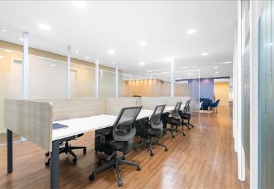Open-plan coworking space with rows of desks and ergonomic chairs.