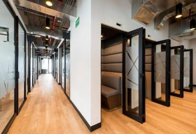 Long hallway with glass-walled private offices and wooden flooring.