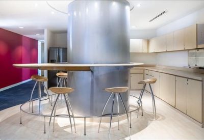 Communal break area with a curved breakfast bar, stools, and kitchen cabinets.