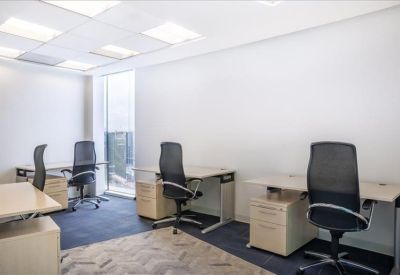 Bright private office featuring three desks and ergonomic black chairs.