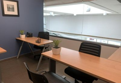 Private internal office with two light wood desks and blue accent wall.